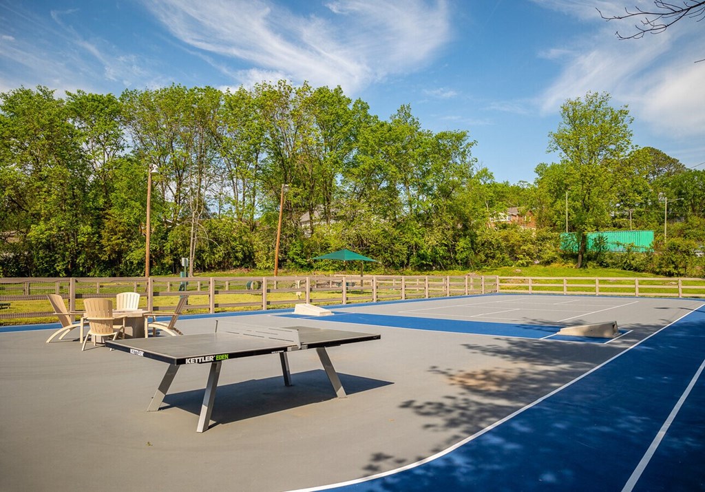A table tennis court with a table tennis table and chairs.