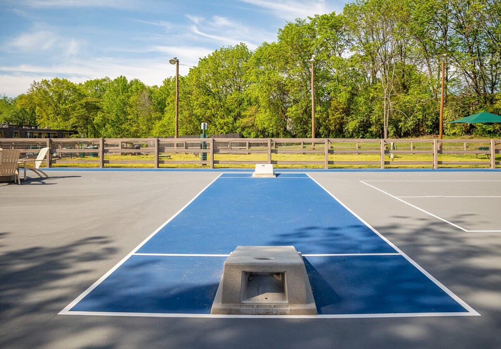 A blue basketball court with a white baseline and a grey ramp.