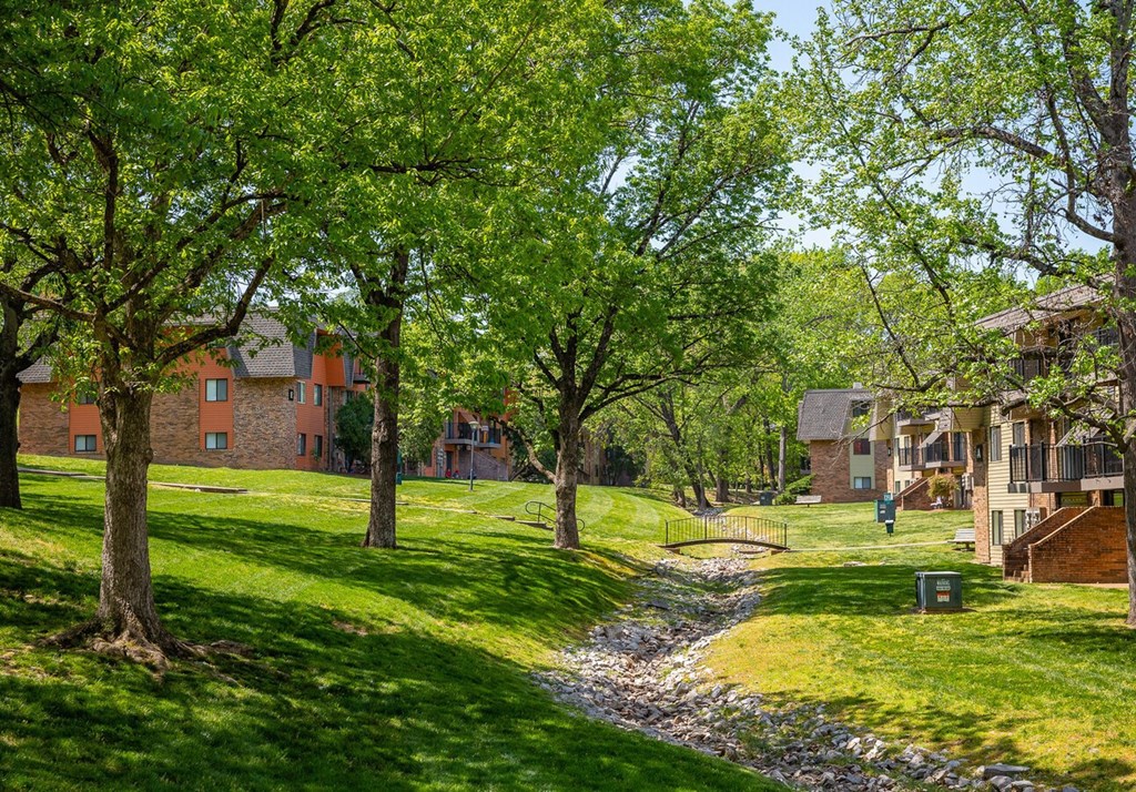 A tree-lined pathway leads to a brick building.