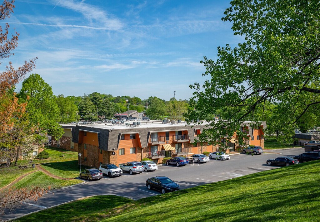 A parking lot in front of a building surrounded by trees.