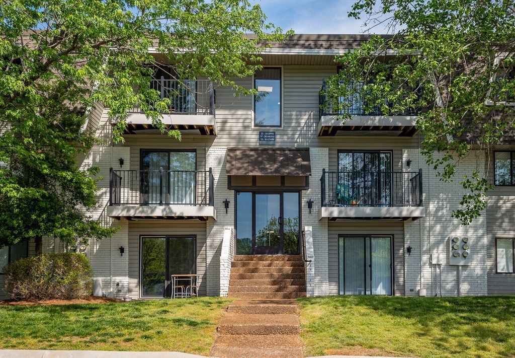 A white two-story apartment building with a balcony on the second floor.