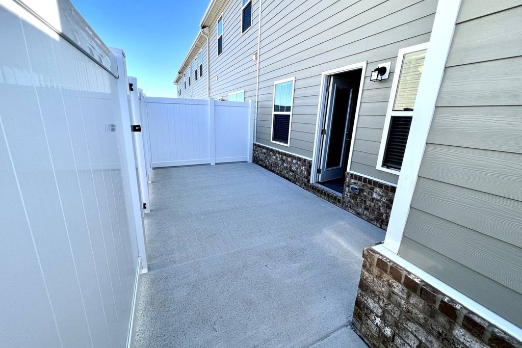 a garage with a white fence and a gray house with a blue sky in the background