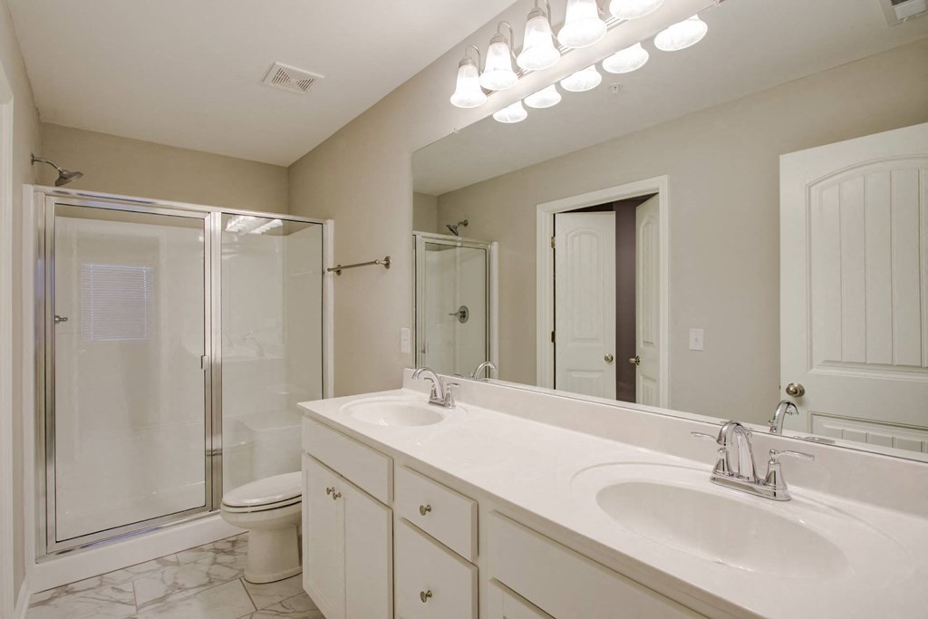 a bathroom with a large mirror and a toilet next to a shower