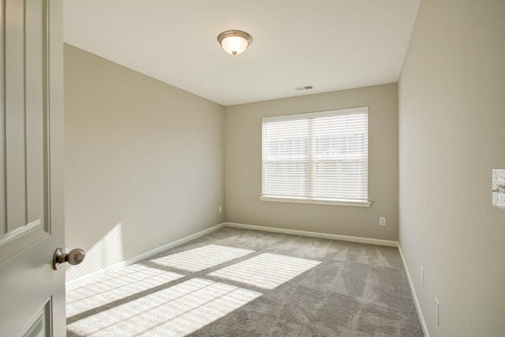 a bedroom with a large window and carpeted flooring