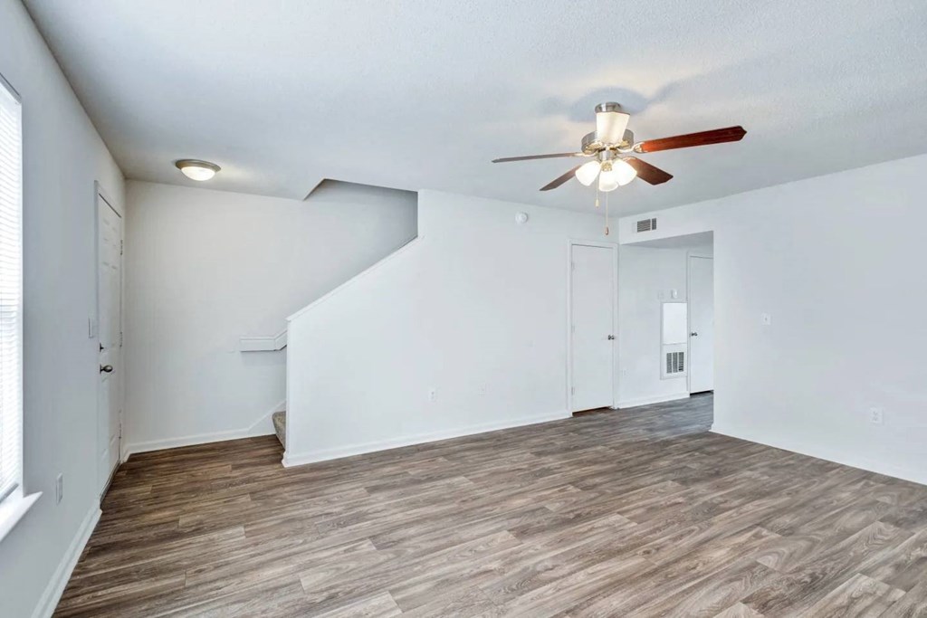 a living room with white walls and a ceiling fan