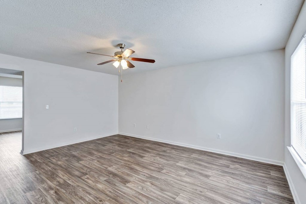 an empty living room with a ceiling fan and a window