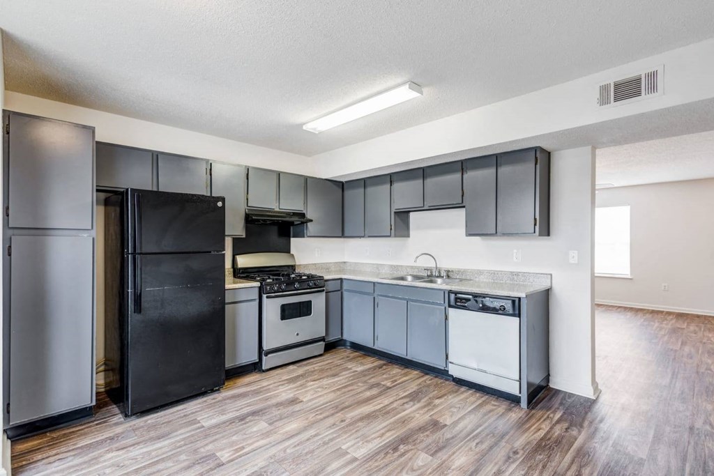 an empty kitchen with stainless steel appliances and black refrigerator