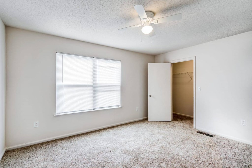 an empty room with a ceiling fan and a window