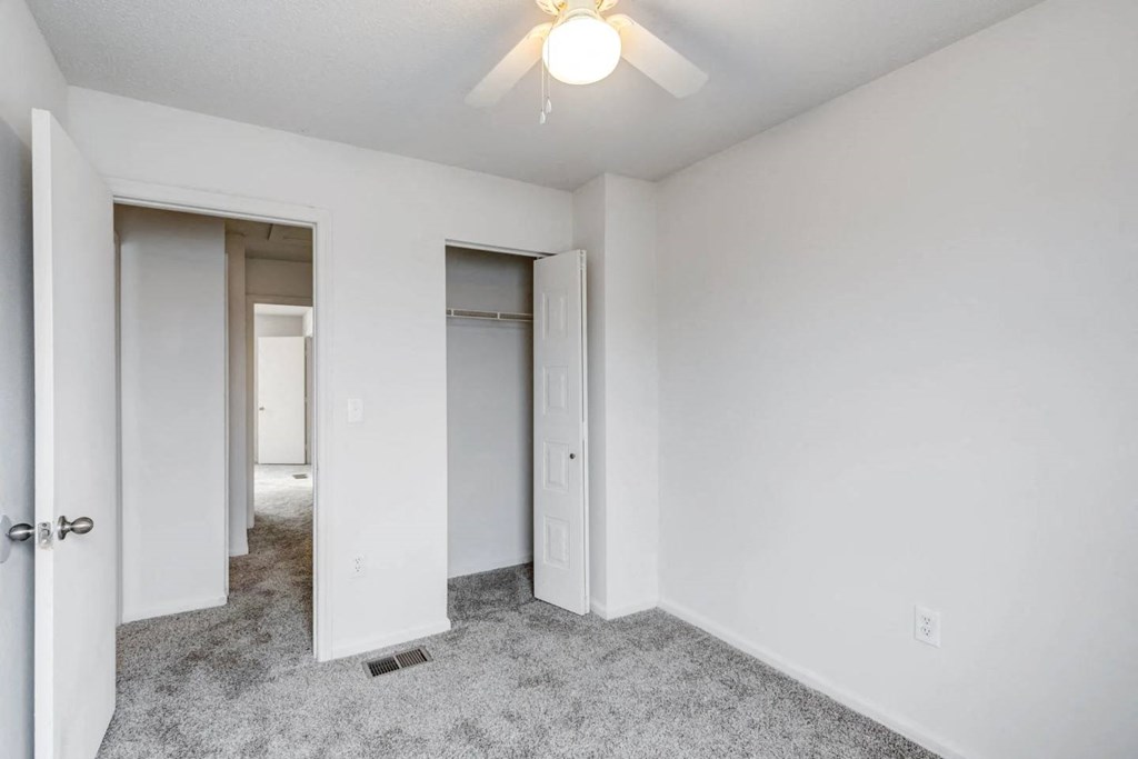 a bedroom with white walls and a ceiling fan
