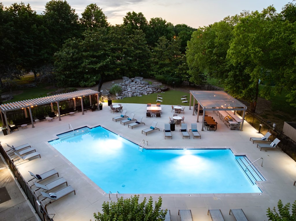A large outdoor swimming pool surrounded by trees and lounge chairs.