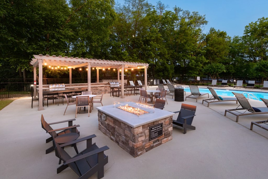 A backyard with a fire pit and chairs.