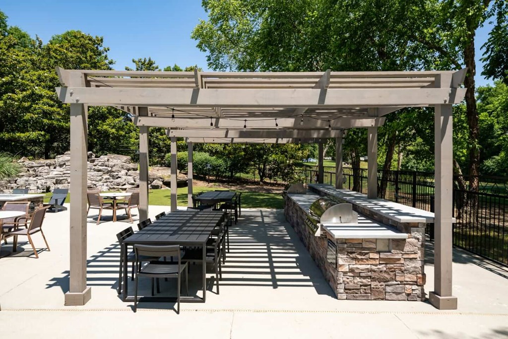 A white pergola with a table and chairs underneath it.