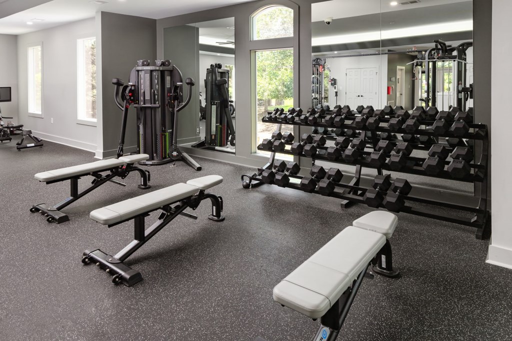 A gym with a variety of equipment including weights and benches.