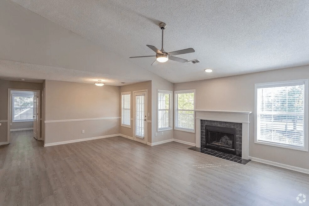 A spacious living room with a fireplace and a ceiling fan.