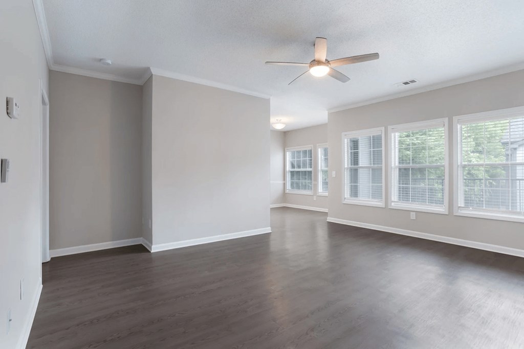 Empty room with a ceiling fan and large windows.