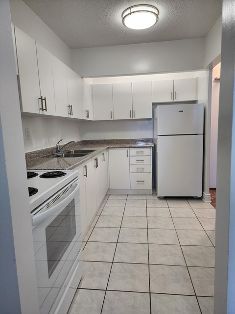 A kitchen with white appliances and cabinets.
