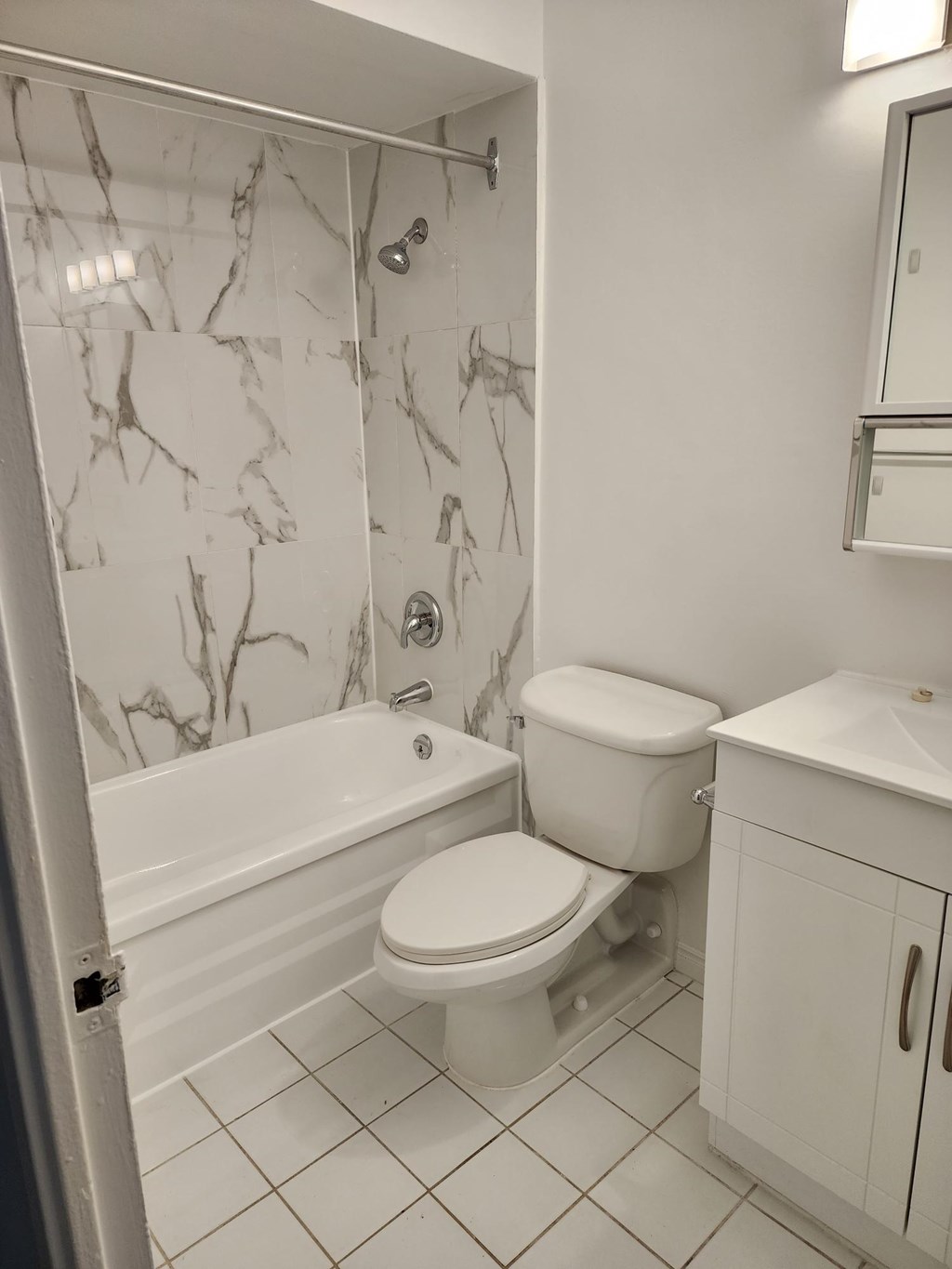 A white toilet sits in a bathroom with a marble shower.