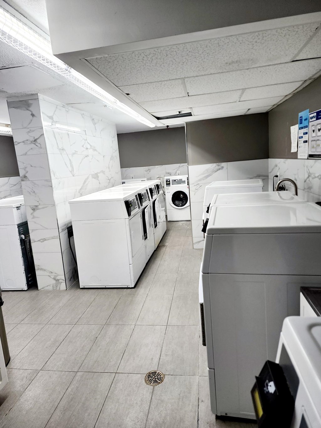 A laundromat with a washer and dryer on the left and a washer and dryer on the right.