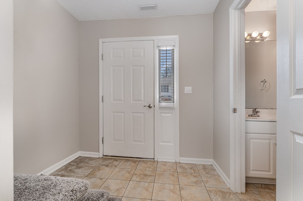 a bedroom with a white door and a bathroom with a sink and mirror