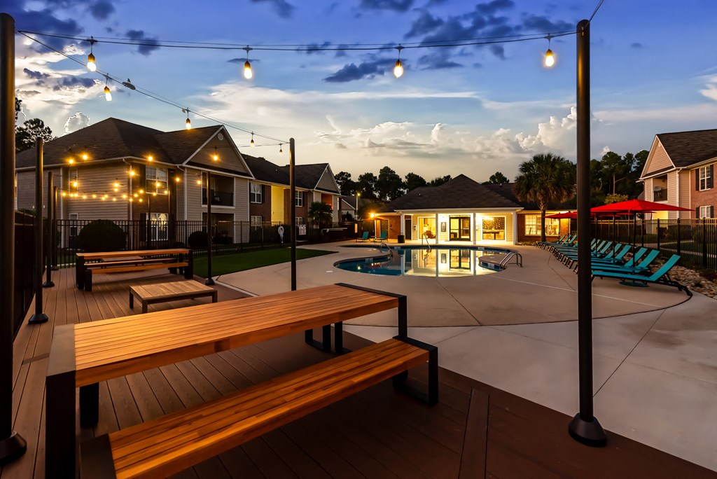 an outdoor patio with benches and a pool at dusk