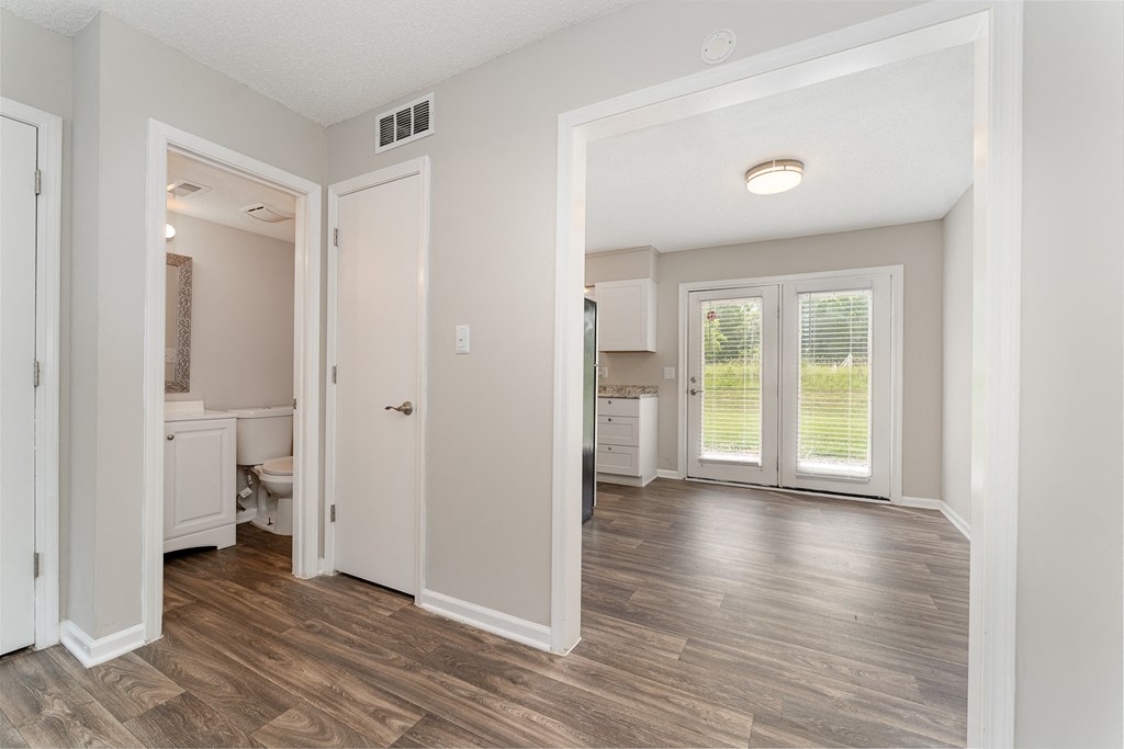 a bedroom with hardwood flooring and a doorway leading to a bathroom