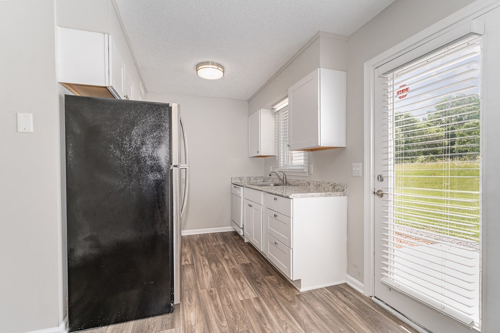 a kitchen with white cabinets and a black refrigerator