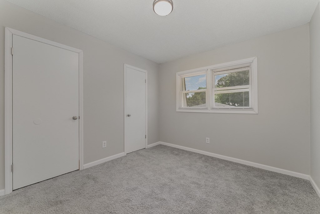 a bedroom with grey walls and carpet
