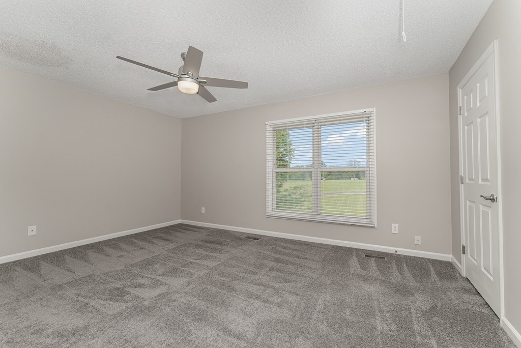 an empty bedroom with a ceiling fan and a window