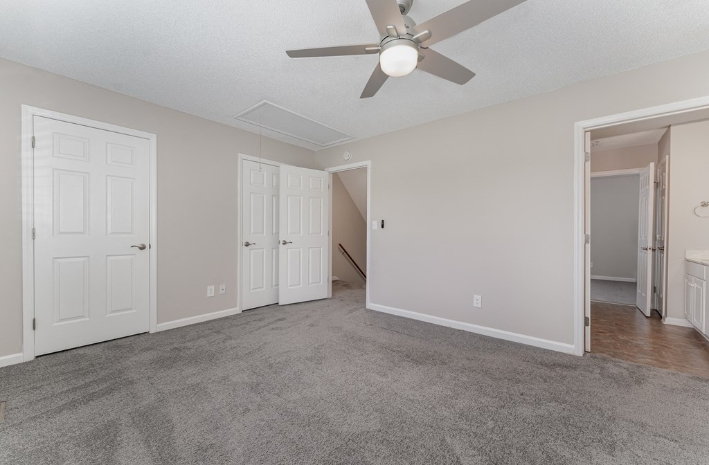 a bedroom with two closets and a ceiling fan