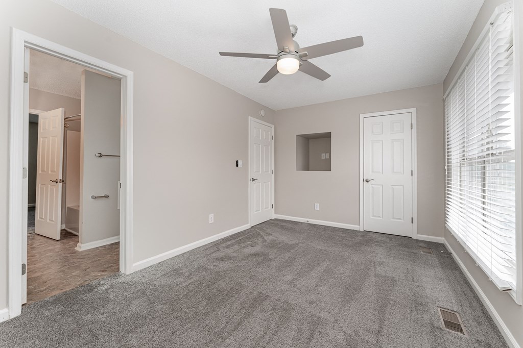 a bedroom with a ceiling fan and window