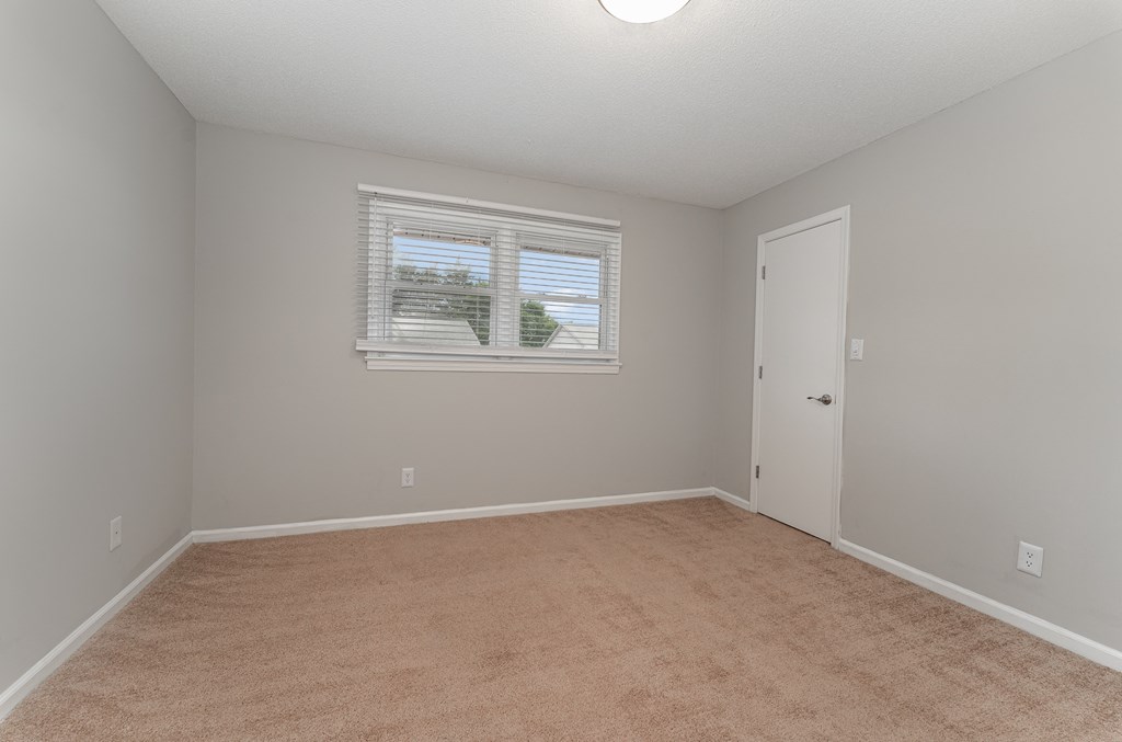a bedroom with a carpeted floor and a window