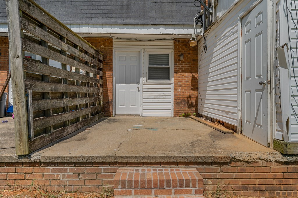 a front porch with a white door and a wooden fence