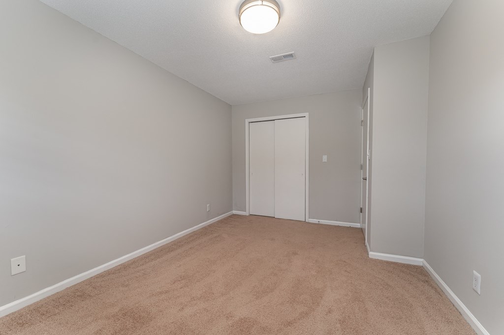 a bedroom with a carpeted floor and a door to a closet