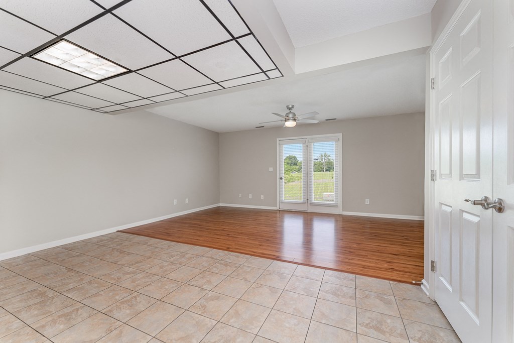 an empty living room with a tile floor and a ceiling fan