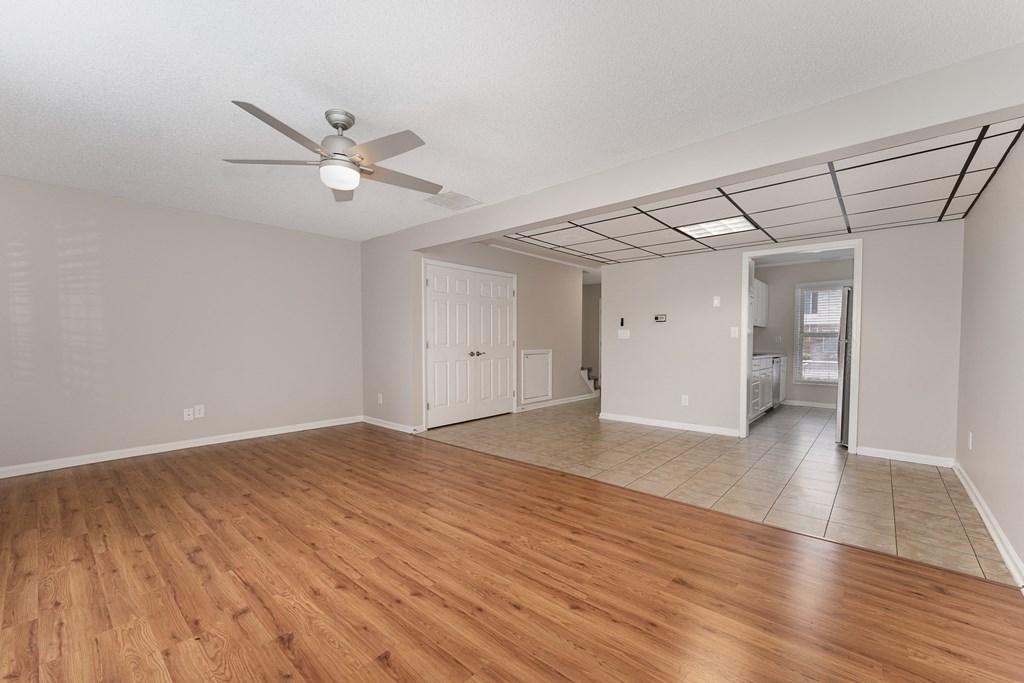 an empty living room with a ceiling fan and a tiled floor