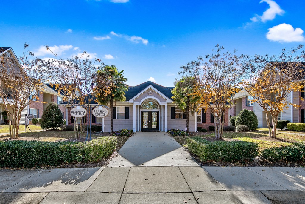 a white house with a sidewalk and trees in front of it