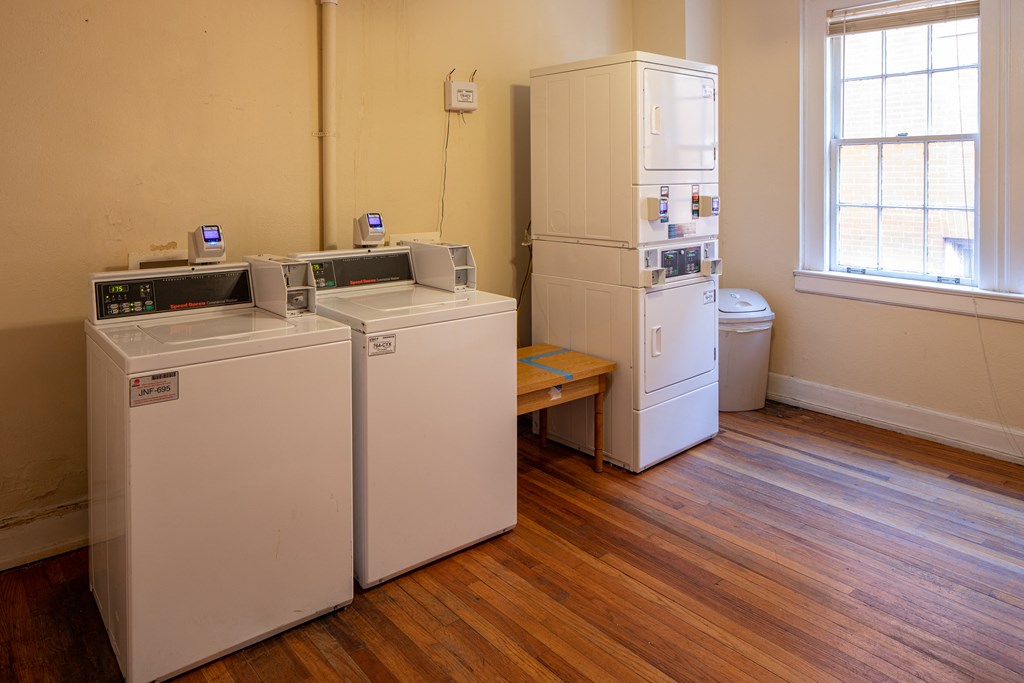 two washing machines and a refrigerator in a room with wooden floors
