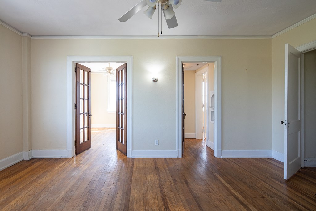 an empty living room with wood floors and a ceiling fan