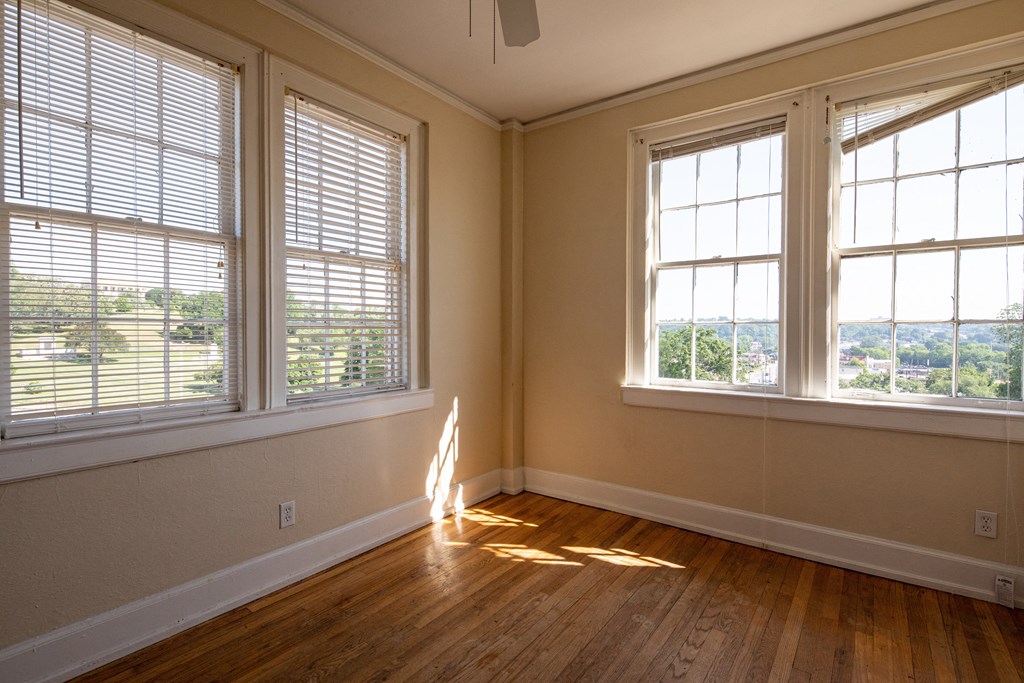 an empty living room with three windows and wood floors