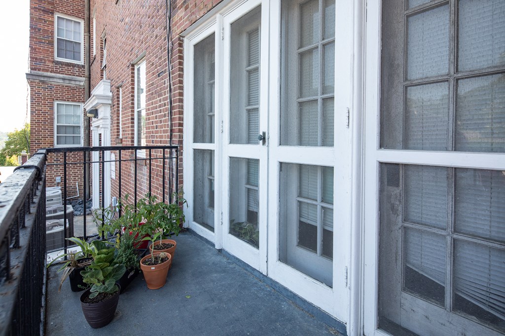 a balcony with potted plants and a door to a brick building