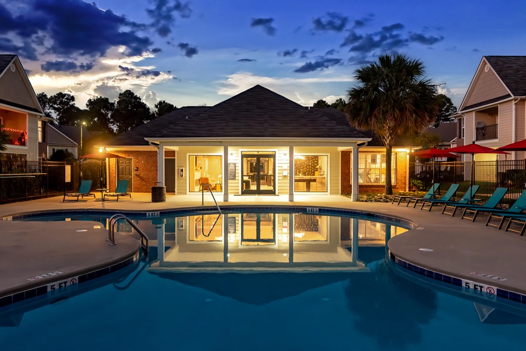 a house with a pool and chairs in front of it