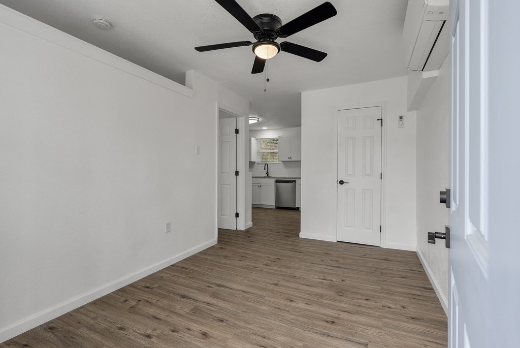 a living room with white walls and a ceiling fan