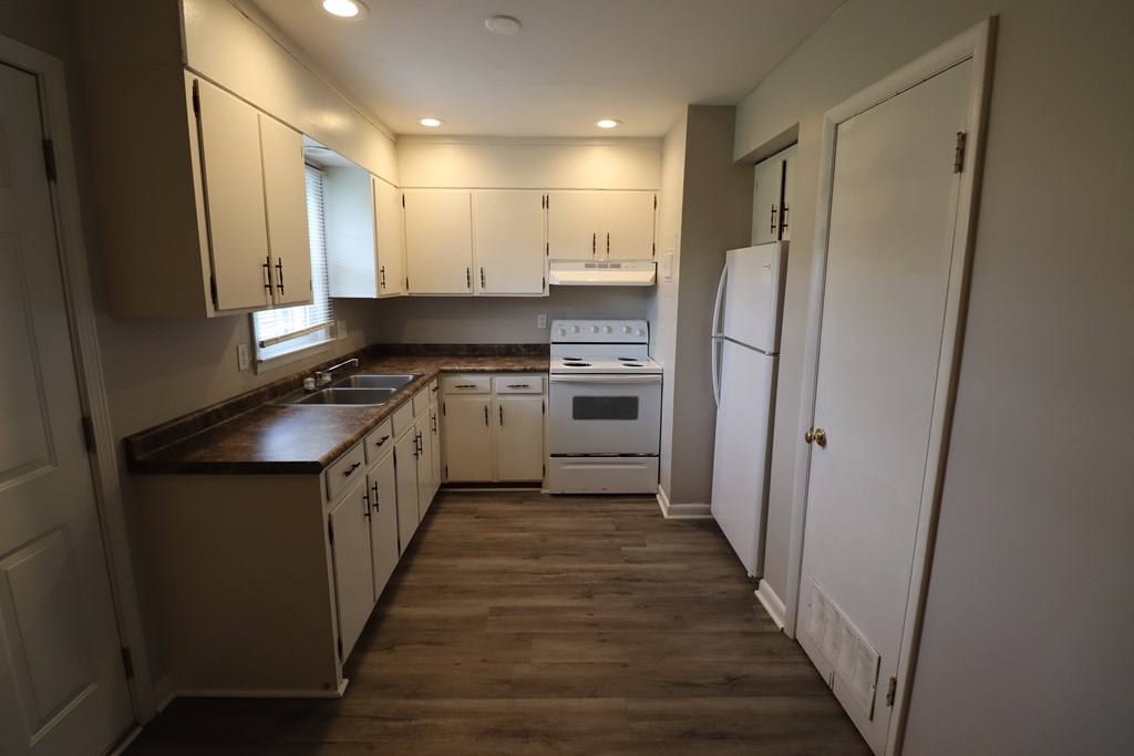 A kitchen with white cabinets and a white refrigerator.