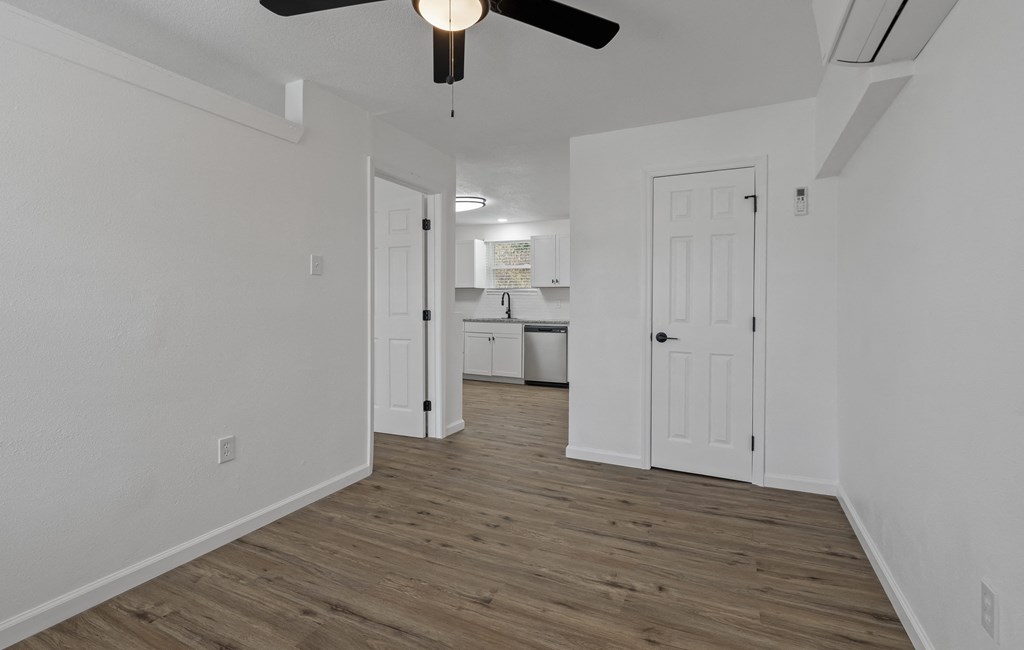 an empty living room with white walls and a ceiling fan