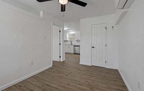 an empty living room with white walls and a ceiling fan
