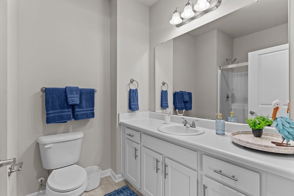 A white bathroom with a toilet, sink, and mirror.