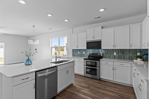 A modern kitchen with white cabinets and a wooden floor.