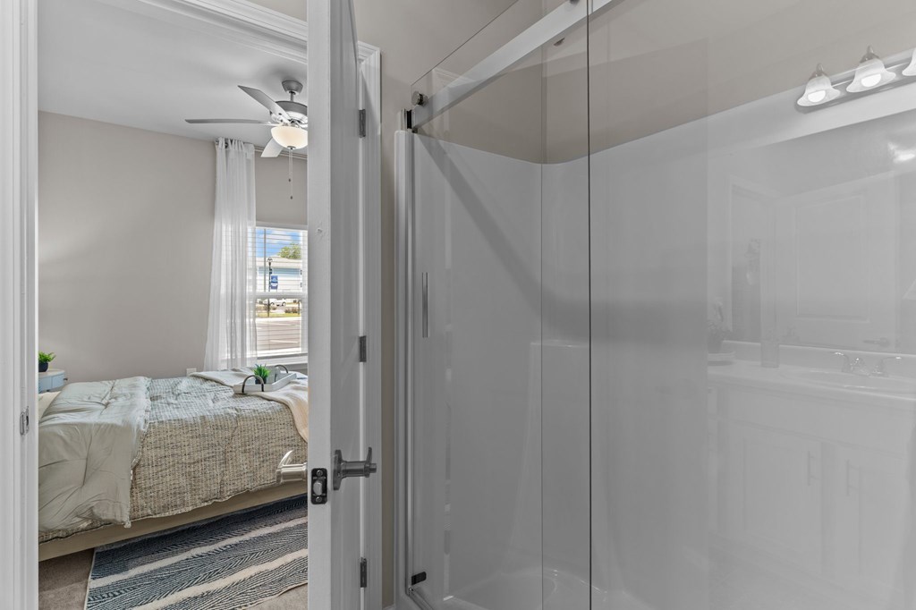 A bedroom with a bed and a glass door leading to a bathroom.