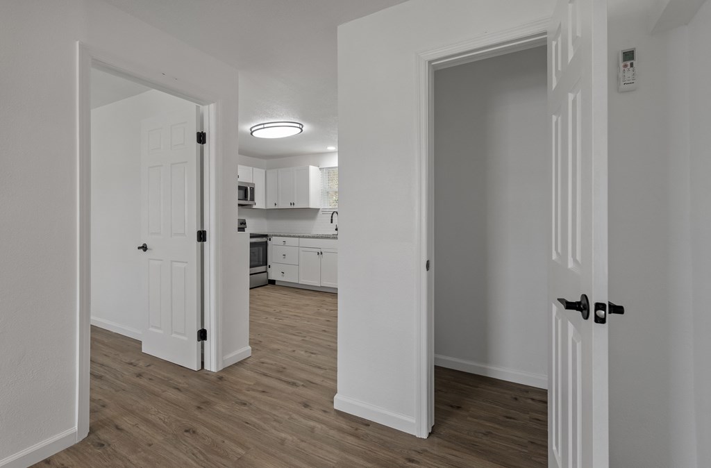 a renovated living room and kitchen with white walls and wood flooring