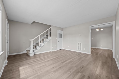 A spacious room with a staircase and a door leading to another room.